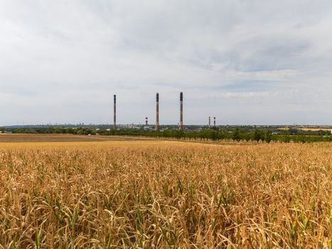 Aerial view of Danube Power Plant in Szazhalombatta Hungary with gas fired thermal units smokestacks surrounding farmland and cornfields under a cloudy sky. Aerial view of Danube Power Plant in Szazhalombatta Hungary with gas fired thermal units smokestacks surrounding farmland and cornfields under a cloudy sky.