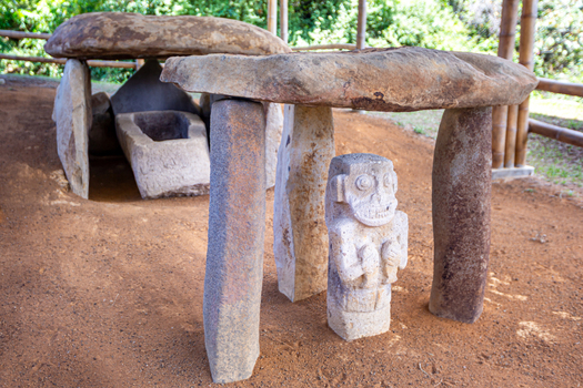 View of ancient stone statues and a megalithic tomb structure at San Agustin Archaeological Park in San Agustin Huila Colombia.