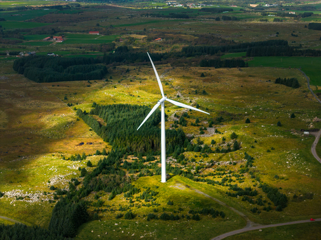 Aerial view of Hog Jaeren vindkraftverk wind turbine set in a rural landscape with green fields rocky terrain and patches of forest in Ha Municipality Rogaland Norway.