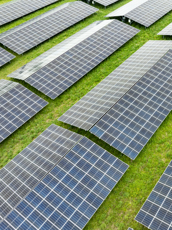 Aerial view of rows of solar panels on a green field under bright daylight in Aiglsbach Bavaria Germany.