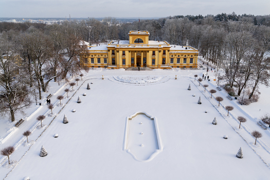 Aerial view of Traku Voke Manor with its yellow facade snow covered courtyard and people walking in winter in Vilnius Vilniaus apskritis Lithuania.