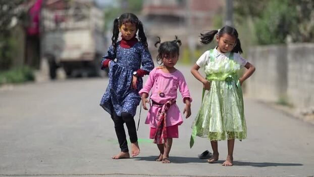 View of three young girls walking on a paved road Nepal.