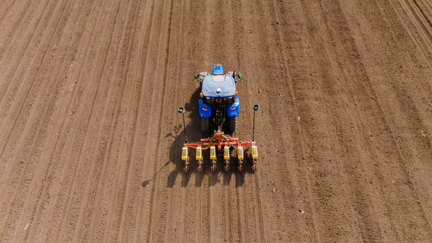 Aerial view of a blue tractor with yellow seeder in a field with brown earth Sremska Mitrovica Vojvodina Serbia. Aerial view of a blue tractor with yellow seeder in a field with brown earth Sremska Mitrovica Vojvodina Serbia.