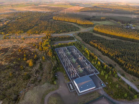 Aerial view of an electrical substation on Eaglesham moor surrounded by dense evergreen forests and open moorland during sunset Kilmarnock Scotland United Kingdom.