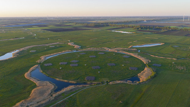 Aerial view of the LOFAR superterp radio telescope station featuring circular antenna arrays on a green island surrounded by water and vast agricultural fields Buinen Drenthe Netherlands. Aerial view of the LOFAR superterp radio telescope station featuring circular antenna arrays on a green island surrounded by water and vast agricultural fields Buinen Drenthe Netherlands.