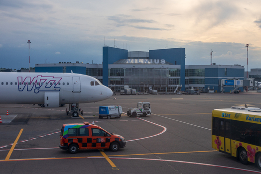 Vilnius Lithuania 04 June 2026 View of Vilnius International Airport with a Wizz Air aircraft parked on the tarmac ground support vehicles and a shuttle bus under a cloudy sky.