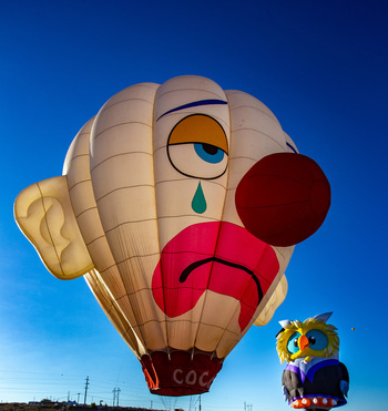 Albuquerque United States 12 October 2017 View of a sad clown balloon floating gently beside a vibrant owl balloon against a backdrop of a clear blue sky. Albuquerque United States 12 October 2017 View of a sad clown balloon floating gently beside a vibrant owl balloon against a backdrop of a clear blue sky.