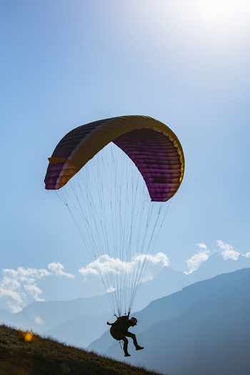 View of a paraglider soaring against a clear blue sky above the mountainous landscape of Booni Khyber Pakhtunkhwa Pakistan.
