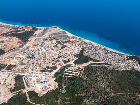 Aerial view of modern coastal development and construction sites along the sandy beach and turquoise waters of the Ionian Sea in Palase Vlore County Albania.