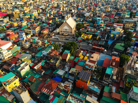 Aerial view of the Iglesia Ni Cristo Maynila Magsaysay church surrounded by dense colorful rooftops and shipping containers in Manila Metro Manila Philippines.