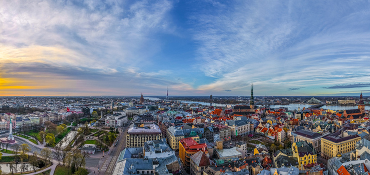 Aerial view of the historic cityscape of Riga featuring the Daugava River iconic church spires and colorful rooftops under a dramatic sunset sky in Riga Latvia. Aerial view of the historic cityscape of Riga featuring the Daugava River iconic church spires and colorful rooftops under a dramatic sunset sky in Riga Latvia.