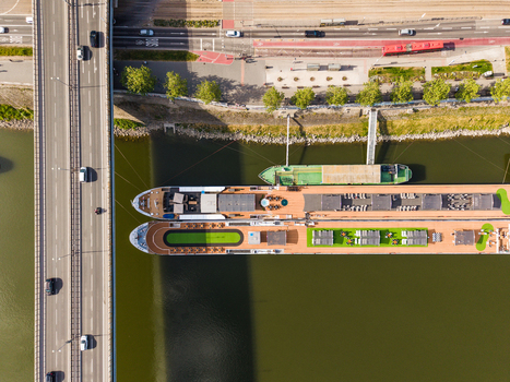 Aerial view of large river cruise ships docked along the Danube riverbank next to a busy bridge and city road in Bratislava Bratislava Region Slovakia. Aerial view of large river cruise ships docked along the Danube riverbank next to a busy bridge and city road in Bratislava Bratislava Region Slovakia.