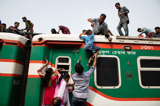 Dhaka Bangladesh 14 June 2018 View of people climbing onto the roof of a crowded green and red train at Airport Railway Station during a busy commute. Dhaka Bangladesh 14 June 2018 View of people climbing onto the roof of a crowded green and red train at Airport Railway Station during a busy commute.