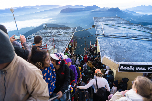 Ratnapura Sri Lanka 23 February 2026 View of a large crowd of pilgrims and tourists gathered on the summit of Adam s Peak at dawn overlooking misty mountain ranges.