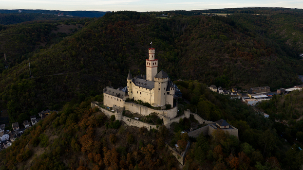 Aerial view of Marksburg castle perched on a hilltop surrounded by dense forest and rolling hills in Braubach Rhineland Palatinate Germany. Aerial view of Marksburg castle perched on a hilltop surrounded by dense forest and rolling hills in Braubach Rhineland Palatinate Germany.