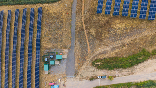 Aerial view of a solar farm with rows of photovoltaic panels battery storage units and electrical transformers situated in a rural landscape in Bedford England United Kingdom. Aerial view of a solar farm with rows of photovoltaic panels battery storage units and electrical transformers situated in a rural landscape in Bedford England United Kingdom.
