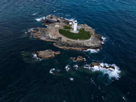 Aerial view of Godrevy Lighthouse situated on a rocky island surrounded by the dark blue waters of the Atlantic Ocean in Gwithian England United Kingdom. Aerial view of Godrevy Lighthouse situated on a rocky island surrounded by the dark blue waters of the Atlantic Ocean in Gwithian England United Kingdom.