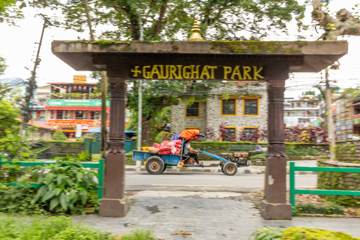Pokhara Nepal 31 July 2026 View of the entrance gate to Gaurighat Park with a person driving a small motorized cart loaded with goods passing by.