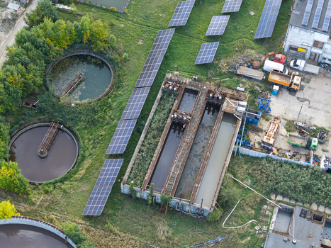 Aerial view of a wastewater treatment plant featuring circular sedimentation tanks and rows of solar panels in Krakow Lesser Poland Voivode Poland.