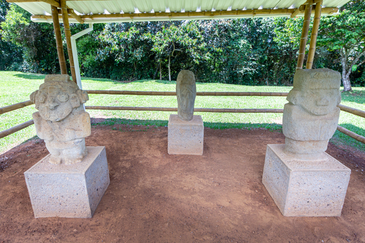 View of San Agustin Archaeological Park featuring ancient pre Columbian stone statues standing on pedestals under a bamboo shelter in San Agustin Huila Colombia.