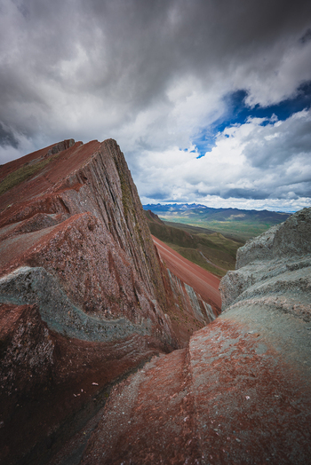 View of the sharp colorful rock ridges of Pallay Punchu Rainbow Mountain under a dramatic cloudy sky in Layo Cuzco Peru. View of the sharp colorful rock ridges of Pallay Punchu Rainbow Mountain under a dramatic cloudy sky in Layo Cuzco Peru.