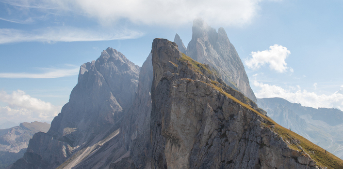 View of the jagged peaks of the Dolomites with steep rocky ridges under a blue sky with light clouds in Rocca Pietore Veneto Italy. View of the jagged peaks of the Dolomites with steep rocky ridges under a blue sky with light clouds in Rocca Pietore Veneto Italy.