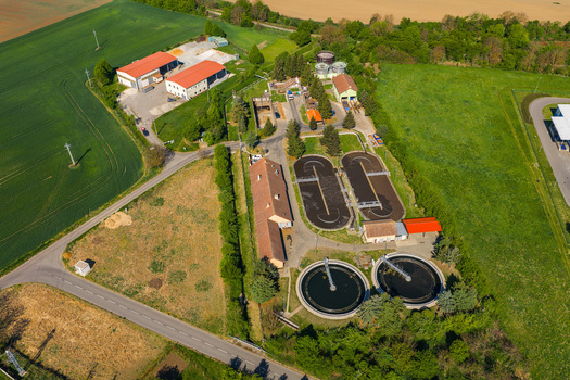 Aerial view of a wastewater treatment plant with circular sedimentation tanks and aeration basins surrounded by green fields in Kyjov South Moravian Region Czechia.