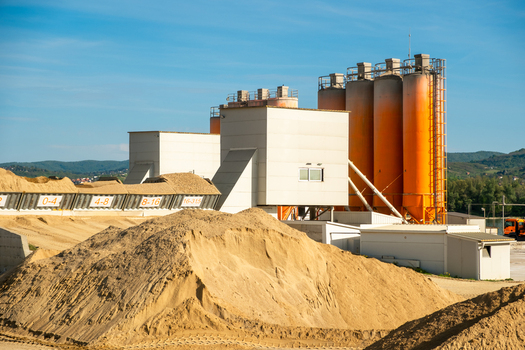 View of an industrial facility with large storage silos and piles of sand under a clear blue sky Novi Sad Vojvodina Serbia. View of an industrial facility with large storage silos and piles of sand under a clear blue sky Novi Sad Vojvodina Serbia.