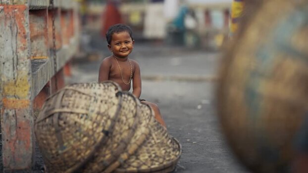 View of a smiling young boy sitting near woven baskets Bangladesh. View of a smiling young boy sitting near woven baskets Bangladesh.