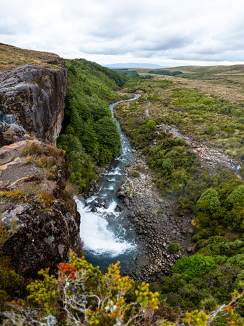View of a cascading waterfall plunging into a rocky riverbed surrounded by lush greenery under a cloudy sky Taranaki Falls Manawatu Whanganui Region New Zealand. View of a cascading waterfall plunging into a rocky riverbed surrounded by lush greenery under a cloudy sky Taranaki Falls Manawatu Whanganui Region New Zealand.