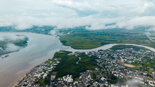 Aerial view of the Kwa Ibo River estuary flowing into the Atlantic Ocean featuring lush mangroves and coastal residential areas in Kwa Ibo Akwa Ibom Nigeria.