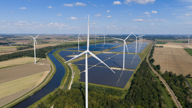 Aerial view of Zonnepark Eekerpolder featuring rows of solar panels and wind turbines situated in a rural landscape with a canal and agricultural fields in Scheemda Groningen Netherlands. Aerial view of Zonnepark Eekerpolder featuring rows of solar panels and wind turbines situated in a rural landscape with a canal and agricultural fields in Scheemda Groningen Netherlands.