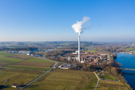 Aerial view of Liapor GmbH Co. KG industrial plant with a tall chimney emitting smoke surrounded by fields and the Regnitz river in Hallerndorf Bayern Germany. Aerial view of Liapor GmbH Co. KG industrial plant with a tall chimney emitting smoke surrounded by fields and the Regnitz river in Hallerndorf Bayern Germany.
