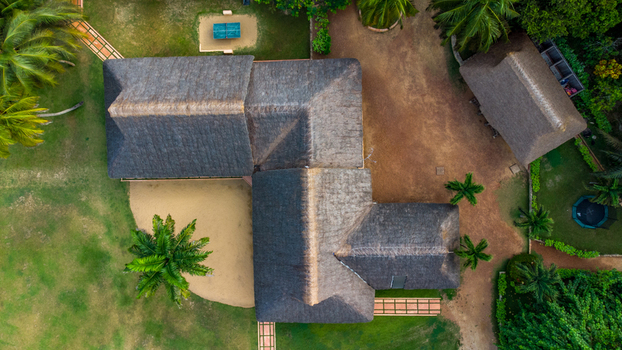 Axim Western Region Ghana 09 February 2023 Aerial view of Lou Moon Resort Eco Luxury featuring a thatched roof building lush palm trees green lawns and sandy pathways. Axim Western Region Ghana 09 February 2023 Aerial view of Lou Moon Resort Eco Luxury featuring a thatched roof building lush palm trees green lawns and sandy pathways.