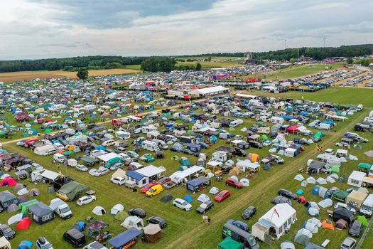Aerial view of the Open Beatz Festival campsite with colorful tents and parked cars on green fields in Herzogenaurach Bayern Germany. Aerial view of the Open Beatz Festival campsite with colorful tents and parked cars on green fields in Herzogenaurach Bayern Germany.