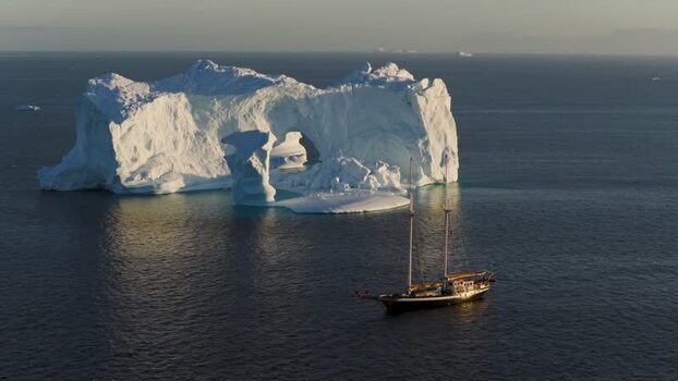 Aerial view of sailboat near arch iceberg in Greenland. Aerial view of sailboat near arch iceberg in Greenland.