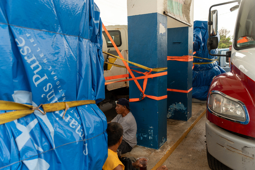 San Jose Tinian Northern Mariana Islands 05 July 2026 View of Samaritan s Purse relief supplies being staged near a truck with local residents resting nearby. San Jose Tinian Northern Mariana Islands 05 July 2026 View of Samaritan s Purse relief supplies being staged near a truck with local residents resting nearby.