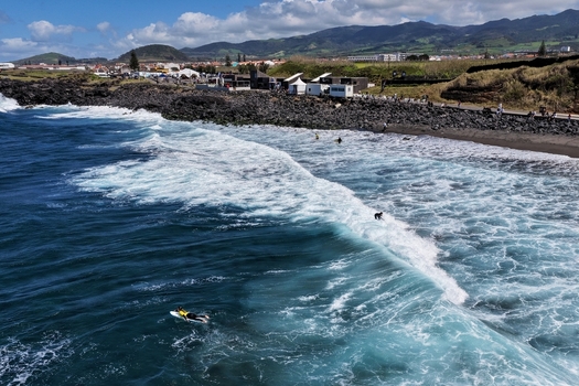 Aerial view of Praia do Areal de Santa Barbara with surfers in the blue ocean waves and volcanic rocks along the coastline Ribeira Grande Acores Portugal. Aerial view of Praia do Areal de Santa Barbara with surfers in the blue ocean waves and volcanic rocks along the coastline Ribeira Grande Acores Portugal.
