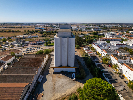 Aerial view of a prominent white grain silo situated in an industrial area with surrounding warehouses and residential buildings in Evora Evora District Portugal. Aerial view of a prominent white grain silo situated in an industrial area with surrounding warehouses and residential buildings in Evora Evora District Portugal.