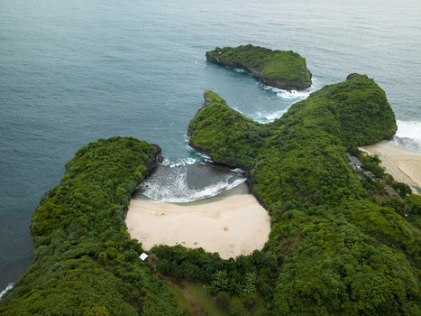 Aerial view of Sedahan Beach where emerald karsts meet a pale sand beach and deep blue ocean Gunungkidul Regency Special Region of Yogyakarta Indonesia. Aerial view of Sedahan Beach where emerald karsts meet a pale sand beach and deep blue ocean Gunungkidul Regency Special Region of Yogyakarta Indonesia.