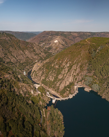 Aerial view of Encoro de Santo Estevo dam spanning the Sil River canyon surrounded by lush green forests and steep rocky slopes in Ourense Ourense Spain. Aerial view of Encoro de Santo Estevo dam spanning the Sil River canyon surrounded by lush green forests and steep rocky slopes in Ourense Ourense Spain.