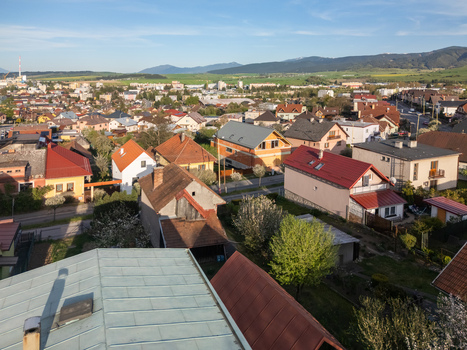 Aerial view of residential houses with colorful rooftops and green gardens under a clear blue sky with mountains in the distance Ruzomberok Zilina Region Slovakia.