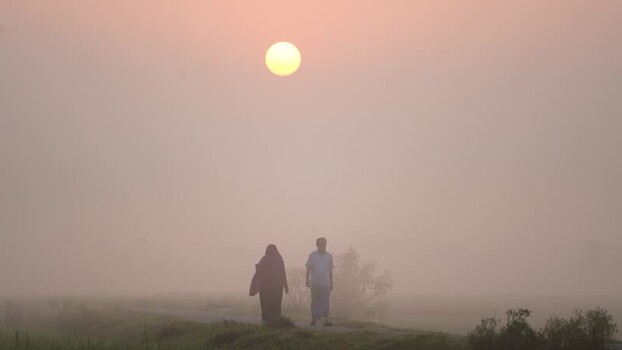 View of people walking in thick fog at sunrise in Bogura Bangladesh.