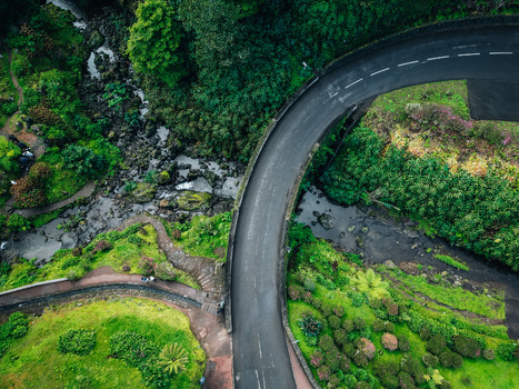 Aerial view of a winding road slicing through vibrant green foliage offering a stark contrast to the dark asphalt Achada Açores Portugal. Aerial view of a winding road slicing through vibrant green foliage offering a stark contrast to the dark asphalt Achada Açores Portugal.
