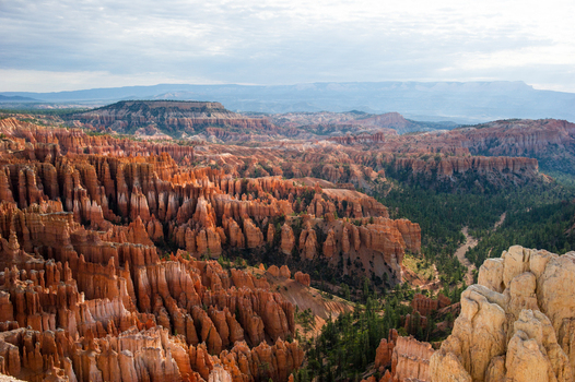 View of Bryce Canyon National Park with its iconic orange hoodoos and pine trees under a cloudy sky in Utah United States.