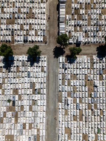 Aerial view of the cemetery with organized rows of white tombstones gravel paths and green trees in Evora Evora District Portugal. Aerial view of the cemetery with organized rows of white tombstones gravel paths and green trees in Evora Evora District Portugal.