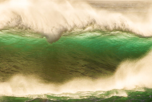 View of a powerful large ocean wave breaking with deep green water and white sea spray at the North Shore in Haleiwa Hawaii United States.
