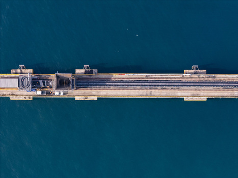 Aerial view of an industrial pier with railway tracks and loading equipment extending into the deep blue sea in Bajos de Haina San Cristobal Province Dominican Republic.