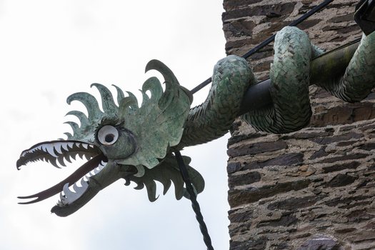 View of a dragon shaped gargoyle with green scales and an open mouth on a stone wall of Eltz Castle in Wierschem Rhineland Palatinate Germany.
