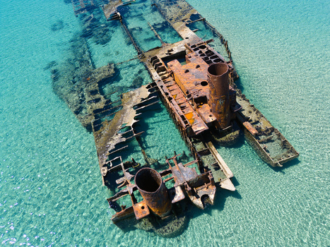Aerial view of the rusty Shipwreck Epanomi submerged in crystal clear turquoise water over a sandy seabed in Epanomi Greece.